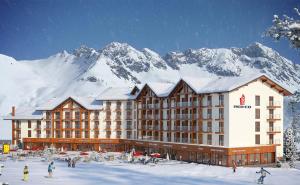 a hotel with a snow covered mountain in the background at Cozy Apartment Near Gondola loft1 in Gudauri