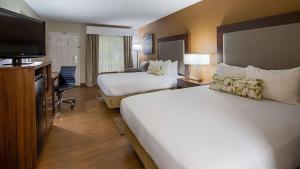 a hotel room with two beds and a flat screen tv at Best Western Shenandoah Inn - Newnan South Atlanta in Newnan