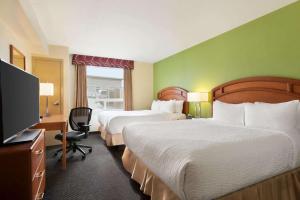 a hotel room with two beds and a flat screen tv at Days Inn & Suites by Wyndham Thompson in Thompson