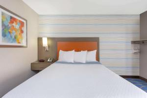 Ce lit se trouve dans une chambre d'hôtel dotée d'un grand lit blanc. dans l'établissement Days Inn by Wyndham Lanham Washington DC, à Lanham