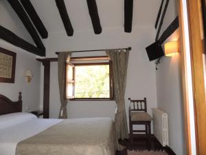 1 Schlafzimmer mit 2 Betten, einem Fenster und einem Stuhl in der Unterkunft Posada Maximo in Espinama
