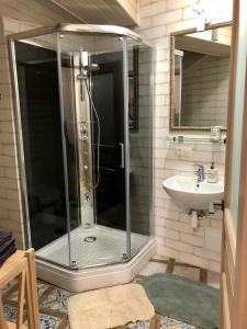 ein Bad mit einer Dusche und einem Waschbecken in der Unterkunft Apartment in Lwiw