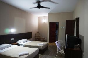 a bedroom with two beds and a ceiling fan at 1 Baron Motel in Kuah