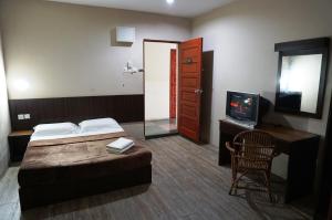 a bedroom with a bed and a tv and a chair at 1 Baron Motel in Kuah