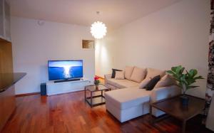 uma sala de estar com um sofá branco e uma televisão de ecrã plano em 2ndhomes Luxury Kamppi Center Apartment with Sauna em Helsinque