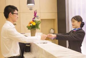 Ein Mann und eine Frau schütteln die Hände an einer Theke in der Unterkunft Atour Hotel Hangzhou Xixi Zijingang in Hangzhou