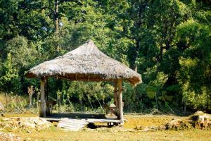 een hut met een grasdak op een veld bij Nature Safari Resort in Bhurkīā