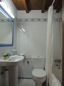 a white bathroom with a toilet and a sink at Posada Maximo in Espinama