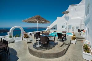 eine Terrasse mit einem Tisch, Stühlen und einem Sonnenschirm in der Unterkunft Nomikos Villas in Fira