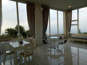 a living room with a table and chairs and windows at Villa batu malang panderman hill in Batu