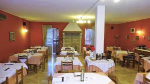 un ristorante con tavoli e sedie bianchi e pareti rosse di Locanda El Piron a Chiampo