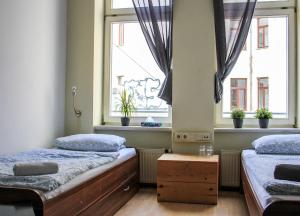 two beds in a room with two windows at Oskars Absteige in Leipzig