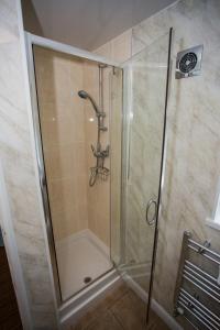 La salle de bains est pourvue d'une douche avec une porte en verre. dans l'établissement The Manor Guest House, à Cheadle