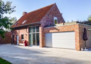 een stenen huis met een witte garagedeur bij De Vakantieschuur in Sint-Laureins