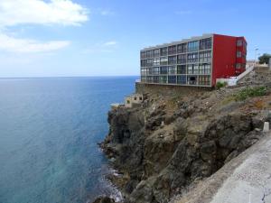 a red building on a cliff next to the ocean at THE BLUE VIEW MASPALOMAS in San Agustin