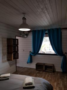a bedroom with a bed and a window with blue curtains at Au Bois Flotté in Hourtin