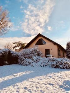 ein Haus mit schneebedeckten Büschen vor einem Haus in der Unterkunft Ferienwohnung Ottokar Familie Dust Nähe Neubrandenburg in Knorrendorf