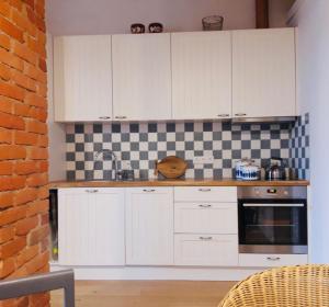 uma cozinha com armários brancos e uma parede de tijolos em Stylish apartment with sauna em Kuressaare