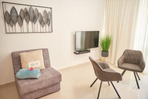 a living room with two chairs and a tv at המקום של אורלי in Eilat
