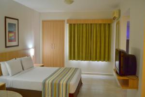 a hotel room with a bed and a television at Suites Hotsprings - Caldas Novas in Caldas Novas