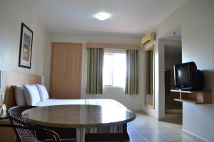 a hotel room with a bed and a table and a tv at Suites Hotsprings - Caldas Novas in Caldas Novas
