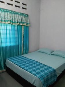 - un lit dans une chambre dotée d'un rideau bleu dans l'établissement Homestay Sri Awana, à Alor Setar