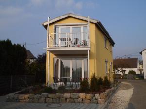 a yellow house with a balcony and a table at Beim Kellerschneider EG in Gundelfingen