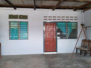 une chambre blanche avec deux portes rouges et une chaise dans l'établissement Homestay Sri Awana, à Alor Setar