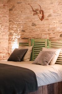 een groot bed in een kamer met een stenen muur bij Les Chambres du Chat in Sainte-Cécile
