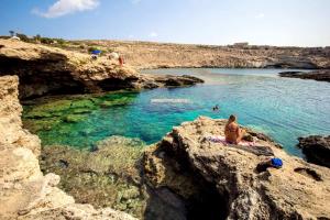 a man sitting on a rock in a body of water at Oasi Di Casablanca in Lampedusa