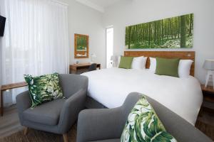 Cette chambre comprend un grand lit et une chaise. dans l'établissement Bamboo Guest House, à Hermanus