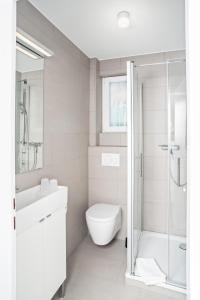 a white bathroom with a toilet and a shower at NordseeHeide-Lodges Cuxhaven in Cuxhaven +36 photos