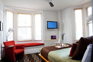 um quarto com uma cama e uma cadeira e uma televisão em The Mosser Hotel em São Francisco