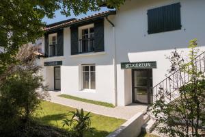 a white building with black windows and a sign on it at Hôtel de la Rhune in Ascain