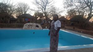 a woman standing in front of a swimming pool at Mukuni Villas in Livingstone