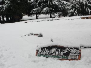 a sign covered in snow in a yard at Ailín Maiá Apartamentos Casa de Montaña in San Carlos de Bariloche