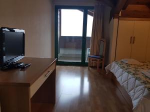 a hotel room with a desk with a tv and a bed at Hotel Oasi in Muggia