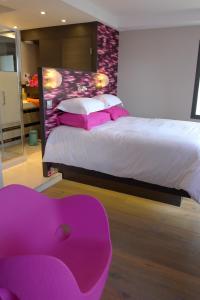 a bedroom with a large bed with a pink chair at Le Clos Du Lac - location de chambres in Veyrier-du-Lac
