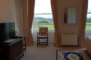 a bedroom with a chair and a large window at Longworth Hall Hotel in Hereford