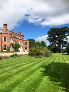 a large grass field in front of a large house at Longworth Hall Hotel in Hereford