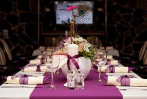 uma mesa com uma toalha de mesa roxa com uma vela e flores em Hotel Pod Hradom em Trenčín