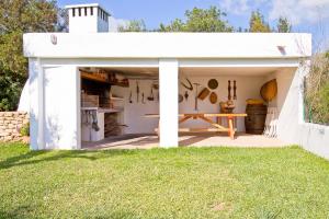 a white shed with a picnic table in a yard at Can Agustín in Santa Gertrudis de Fruitera