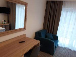 a hotel room with a blue chair and a mirror at Pensjonat Godycki 2 in Pogorzelica