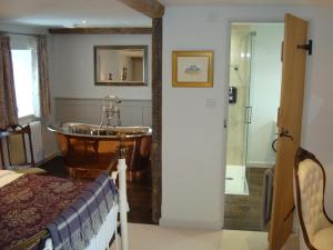 a bedroom with a bathroom with a tub and a sink at Keepers Cottage Guest House in Holt +27 photos