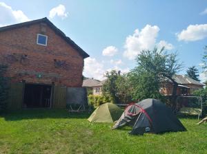 Deux tentes dans l'herbe devant une maison dans l'établissement Bed&Bike Dobra Nuć, à Dubrynychi