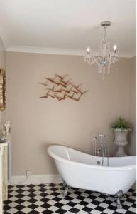 a white bath tub in a bathroom with a chandelier at Longworth Hall Hotel in Hereford