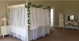 a bedroom with a bed with white curtains and flowers at Longworth Hall Hotel in Hereford