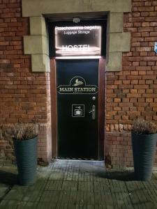 a black door in a brick building with two plants at MainStation in Gdańsk