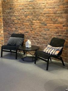 duas cadeiras e uma mesa em frente a uma parede de tijolos em LivingRoom 4B self Check-in 24h em Katowice