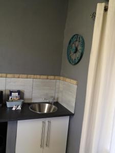ein Badezimmer mit einem Waschbecken und einer Uhr an der Wand in der Unterkunft Elim Guesthouse in Keimoes